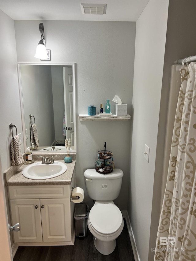 full bath with visible vents, toilet, vanity, wood finished floors, and baseboards