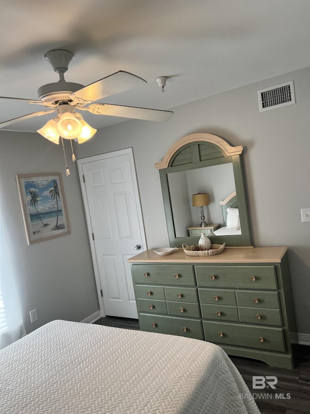 bedroom featuring dark wood-style floors, visible vents, ceiling fan, and baseboards