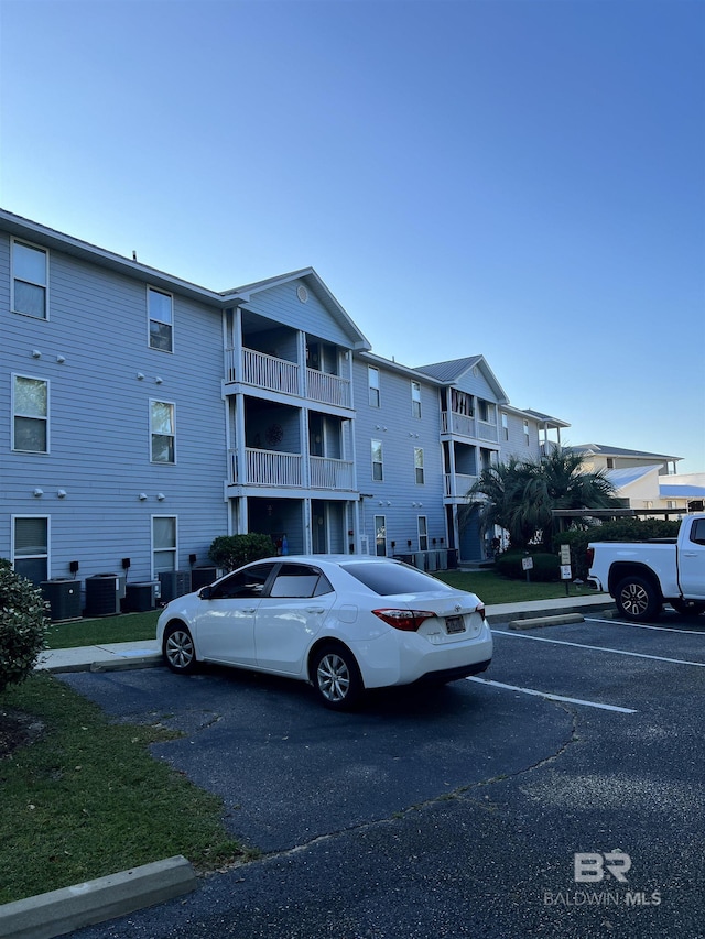 view of building exterior featuring central air condition unit and uncovered parking