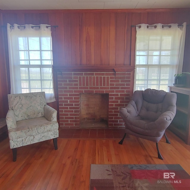 living room featuring a fireplace, wooden walls, and wood finished floors