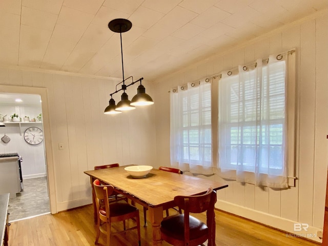 dining room featuring light wood finished floors, baseboards, and ornamental molding