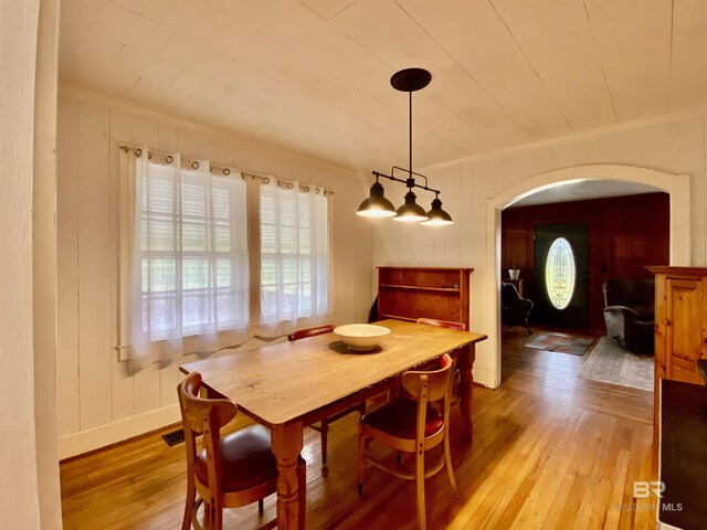 dining area featuring visible vents, arched walkways, light wood-style flooring, and ornamental molding