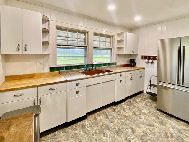 kitchen with open shelves, a sink, white cabinetry, freestanding refrigerator, and crown molding