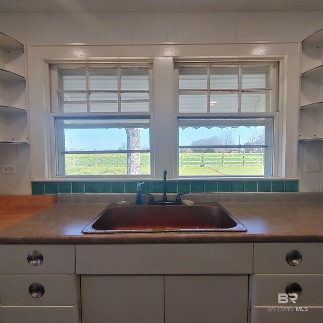 kitchen with open shelves, white cabinets, backsplash, and a sink