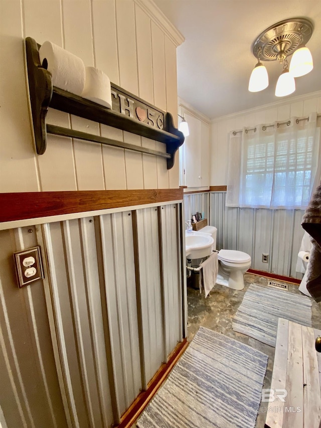 half bath with crown molding, a decorative wall, and toilet