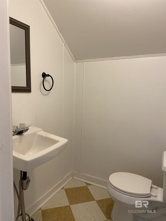 half bath featuring tile patterned floors, toilet, and a decorative wall