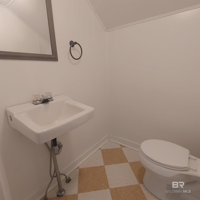 half bathroom featuring tile patterned floors, toilet, and lofted ceiling