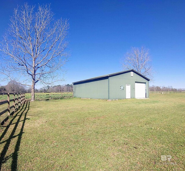 view of pole building featuring a rural view, a yard, and fence