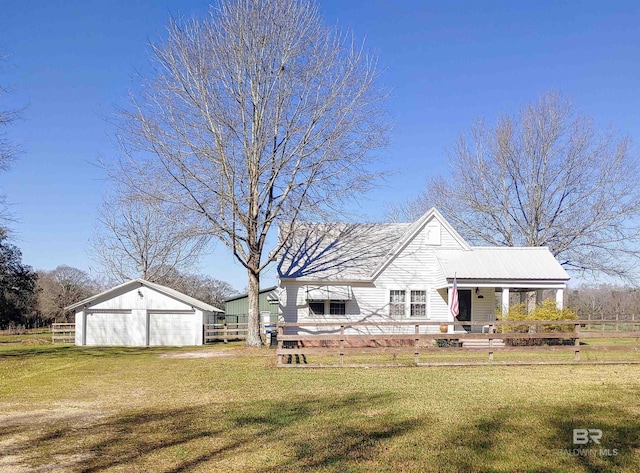 rear view of property featuring an outdoor structure, a yard, and fence