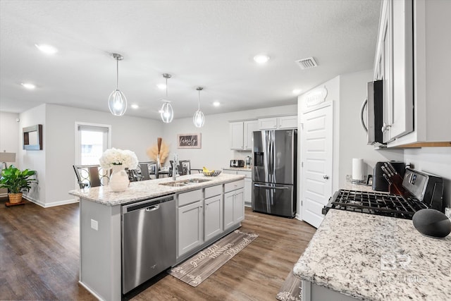 kitchen featuring pendant lighting, dark wood-type flooring, appliances with stainless steel finishes, and a kitchen island with sink