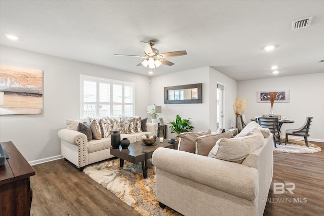 living room featuring ceiling fan and dark hardwood / wood-style floors