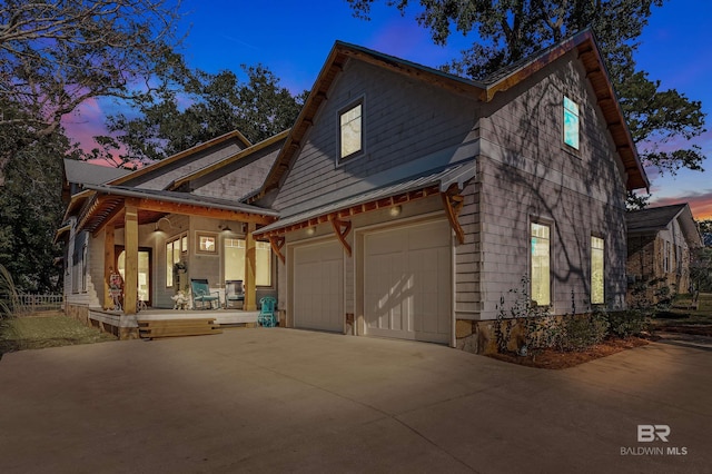 view of side of property with driveway, a porch, and an attached garage