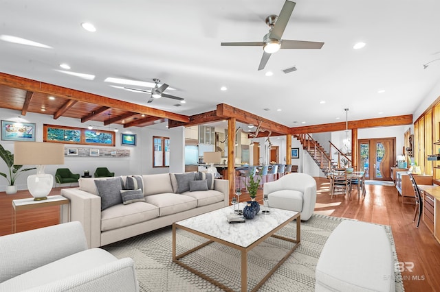 living room featuring recessed lighting, light wood-style flooring, a ceiling fan, beamed ceiling, and stairs