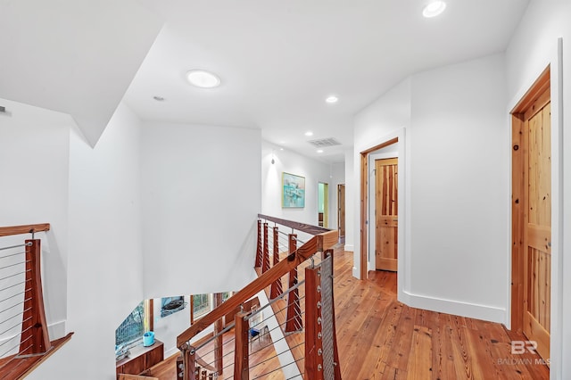 corridor with recessed lighting, visible vents, baseboards, an upstairs landing, and light wood-type flooring