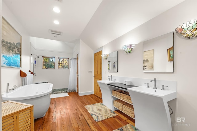 full bath with baseboards, wood-type flooring, curtained shower, vaulted ceiling, and a freestanding tub