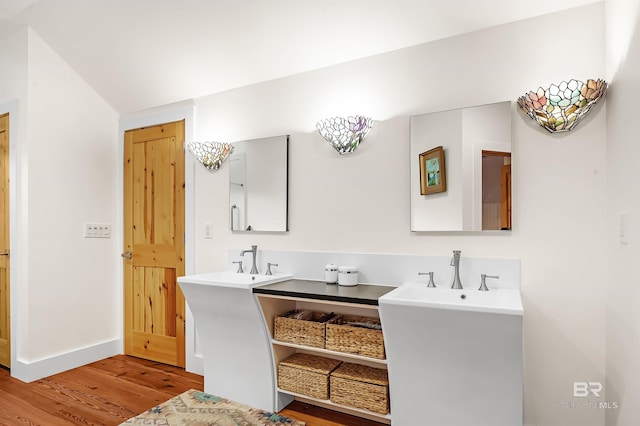 bathroom with double vanity, wood finished floors, and baseboards