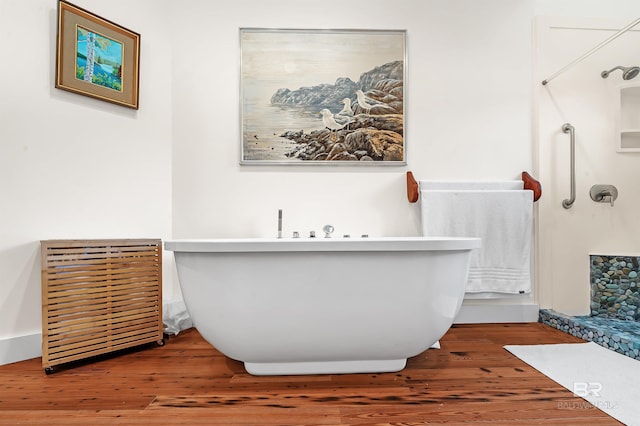 full bathroom featuring a freestanding tub, walk in shower, and wood finished floors