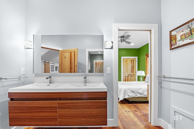 ensuite bathroom with double vanity, connected bathroom, and wood finished floors