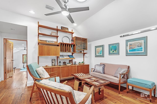 living room featuring lofted ceiling, light wood finished floors, visible vents, and a ceiling fan