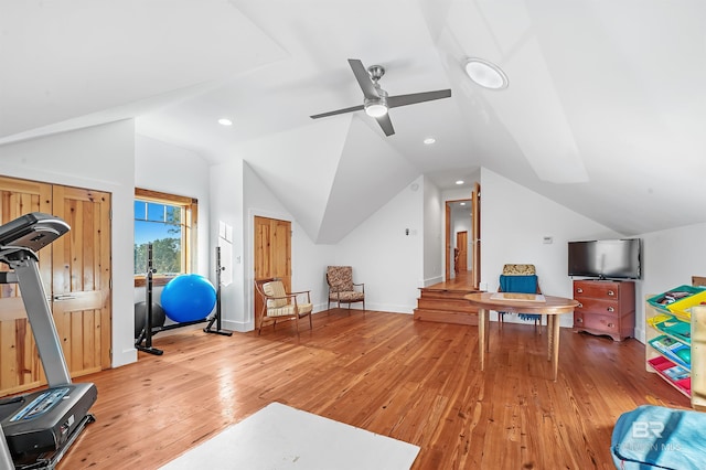 exercise room with lofted ceiling, ceiling fan, light wood-style flooring, and baseboards