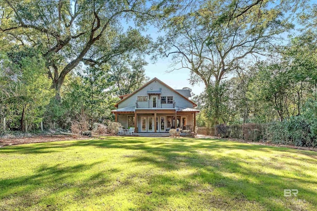 rear view of property featuring a balcony, a porch, and a yard