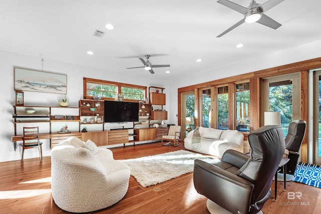 living area with a ceiling fan, visible vents, wood finished floors, and recessed lighting