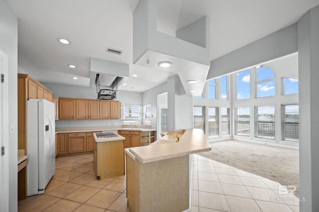 2024 W Beach Blvd, Gulf Shores, AL 36542 - kitchen with white refrigerator with ice dispenser, a towering ceiling, light tile patterned flooring, light carpet, and light countertops