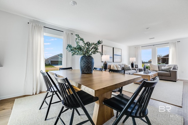 dining area featuring light wood-style flooring, baseboards, and a wealth of natural light