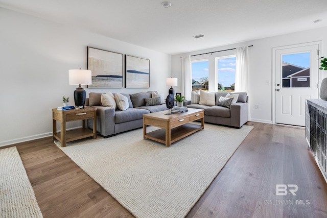 living room featuring visible vents, baseboards, and wood finished floors