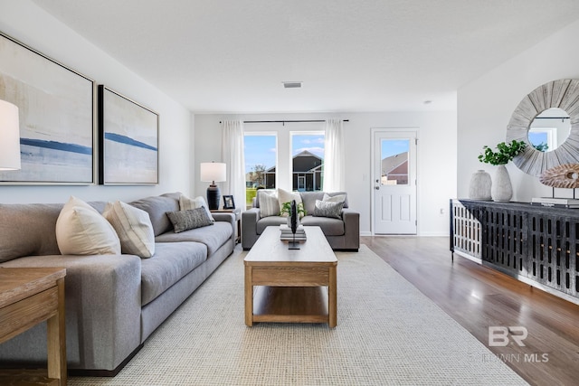 living room featuring baseboards, visible vents, and wood finished floors