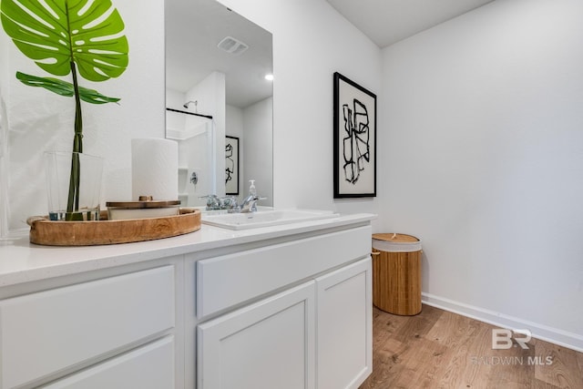 bathroom featuring vanity, wood finished floors, visible vents, and baseboards