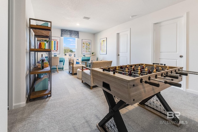 rec room featuring light carpet, visible vents, baseboards, and a textured ceiling