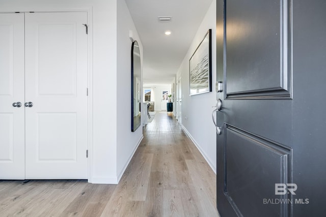 hallway with light wood finished floors, baseboards, visible vents, and recessed lighting