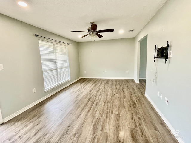 empty room with a textured ceiling, ceiling fan, and light wood-type flooring