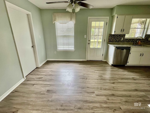 kitchen with tasteful backsplash, dishwasher, sink, white cabinets, and light wood-type flooring