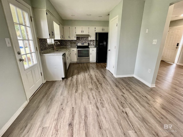 kitchen featuring sink, white cabinets, decorative backsplash, stainless steel appliances, and light wood-type flooring