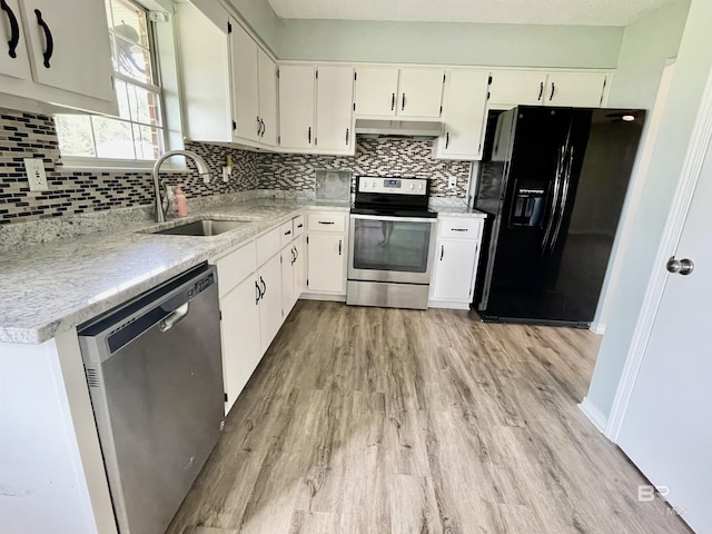 kitchen with appliances with stainless steel finishes, light hardwood / wood-style floors, sink, and backsplash