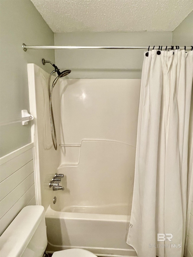 bathroom featuring shower / bath combo with shower curtain, toilet, and a textured ceiling