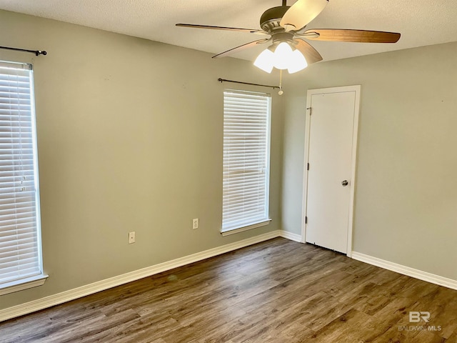 spare room featuring dark wood-type flooring, ceiling fan, and a textured ceiling