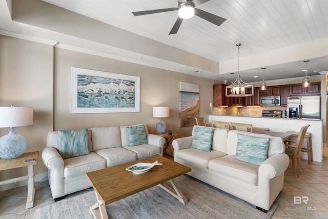 living room with light tile patterned floors, baseboards, a tray ceiling, crown molding, and ceiling fan with notable chandelier