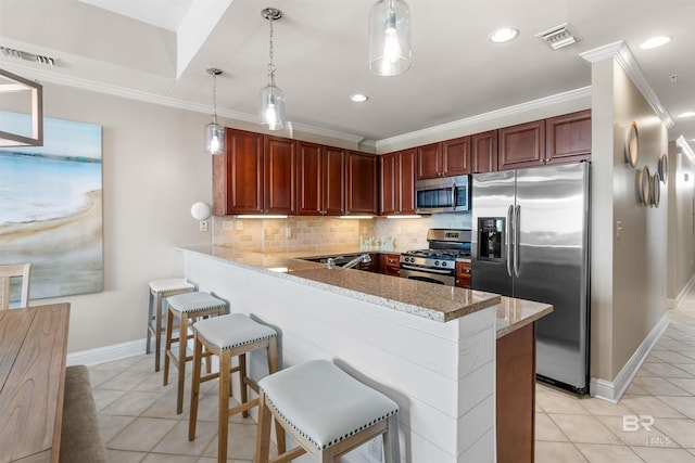 kitchen with a peninsula, appliances with stainless steel finishes, a breakfast bar, and decorative light fixtures