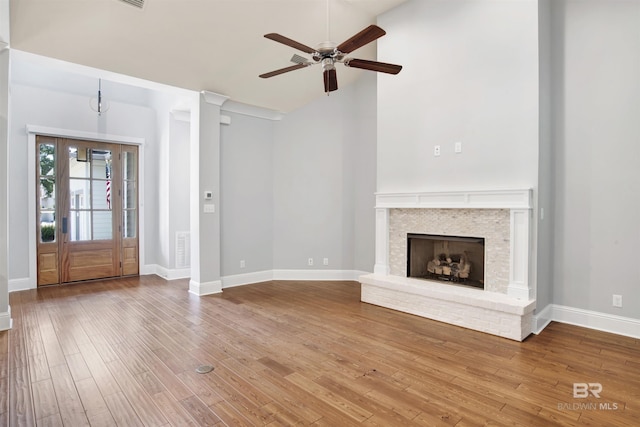 unfurnished living room featuring hardwood / wood-style floors, ceiling fan, vaulted ceiling, and a brick fireplace