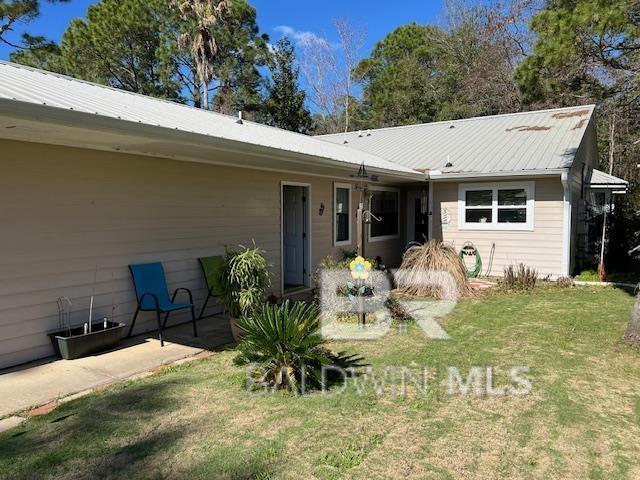 back of property featuring metal roof and a lawn