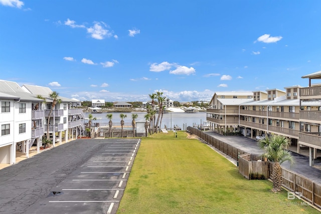 view of home's community featuring uncovered parking, a yard, a water view, and a residential view