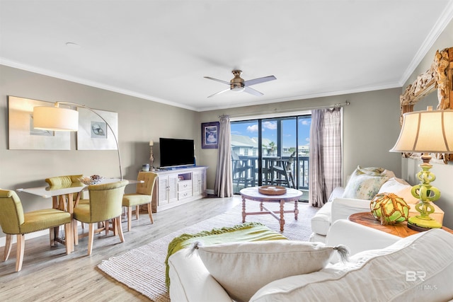 living area featuring wood finished floors, crown molding, a ceiling fan, and baseboards
