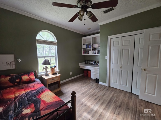 bedroom with visible vents, light wood-style flooring, a textured ceiling, and built in desk