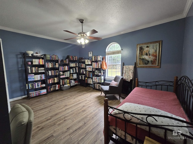 bedroom featuring a textured ceiling, wood finished floors, ceiling fan, and ornamental molding