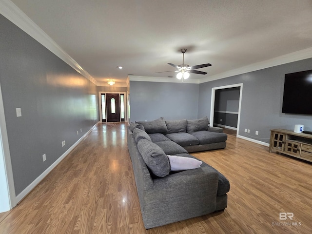living room featuring ornamental molding, ceiling fan, wood finished floors, and baseboards