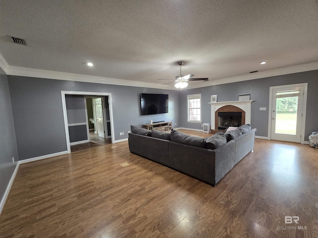 living area featuring a textured ceiling, crown molding, visible vents, ceiling fan, and baseboards