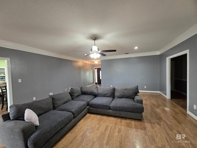 living area featuring baseboards, wood finished floors, a ceiling fan, and ornamental molding